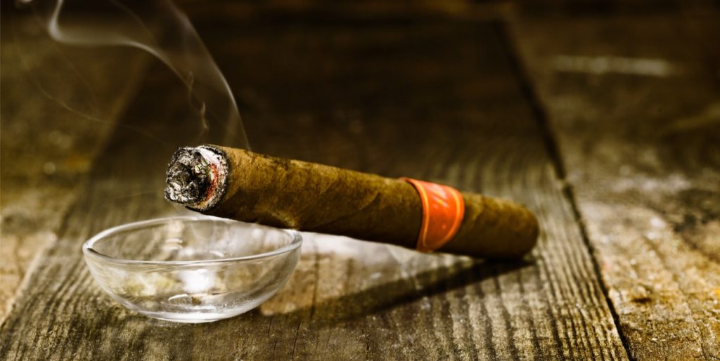 handmade luxury Cuban cigar resting on an ashtray